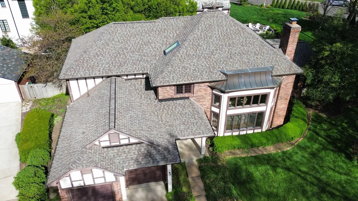 Two-story brick and stucco home with a new weathered-wood shingle roof