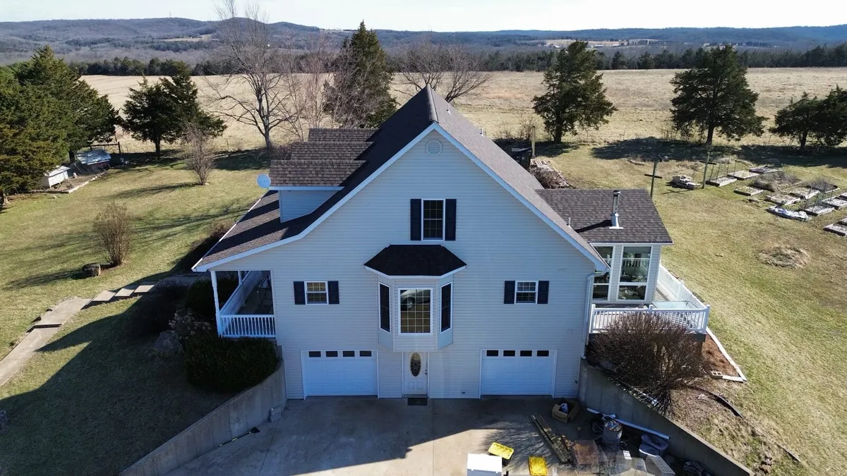 White farmhouse with a new dark roof on a late-fall day