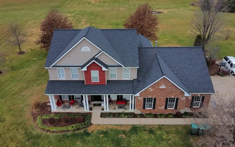 Two-story home with a new roof surrounded by fall trees