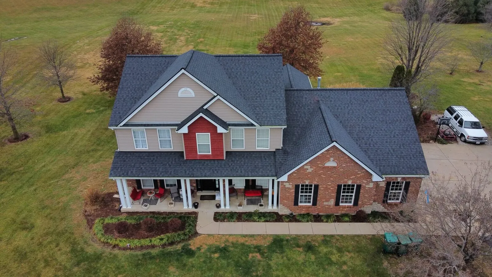 Two-story home with a new roof surrounded by fall trees
