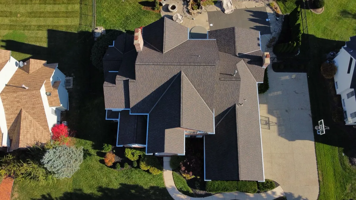 Aerial view of a large home with a complex brown shingle roof